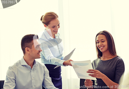 Image of smiling business people with papers in office