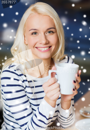 Image of happy young woman drinking tea or coffee