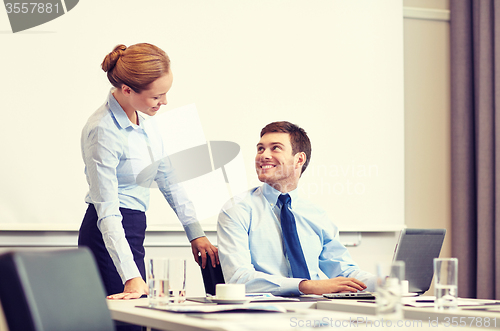 Image of businessman and secretary with laptop in office