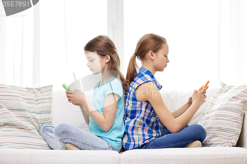 Image of girls with smartphones sitting on sofa at home