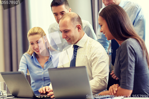 Image of smiling businesspeople with laptops in office