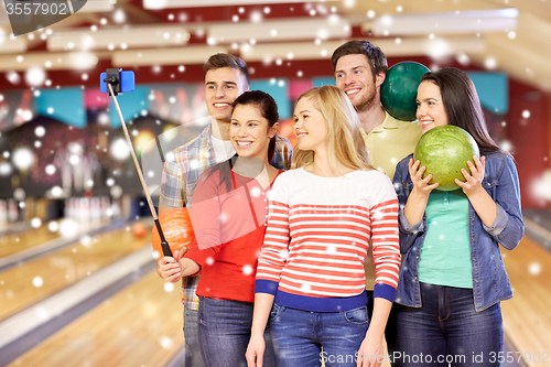 Image of happy friends taking selfie in bowling club
