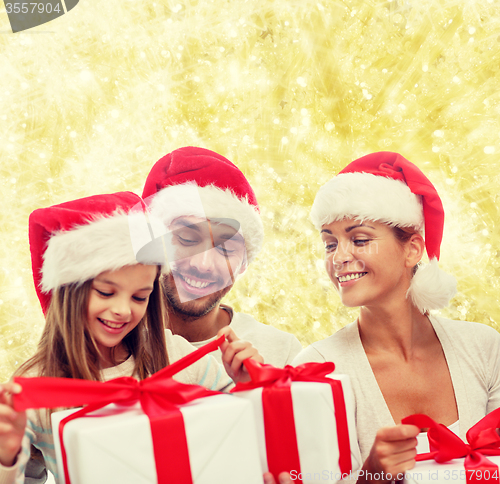 Image of happy family in santa helper hats with gift boxes