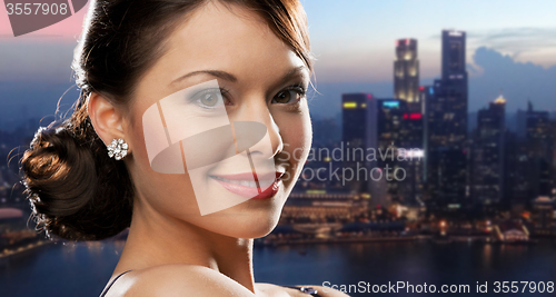 Image of happy woman with diamond earring over night city