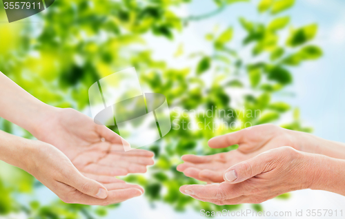 Image of close up of senior and young woman hands