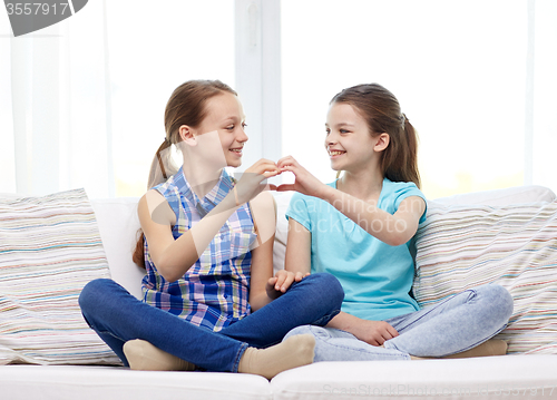 Image of happy little girls showing heart shape hand sign