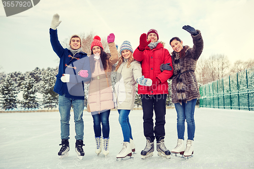 Image of happy friends ice skating on rink outdoors