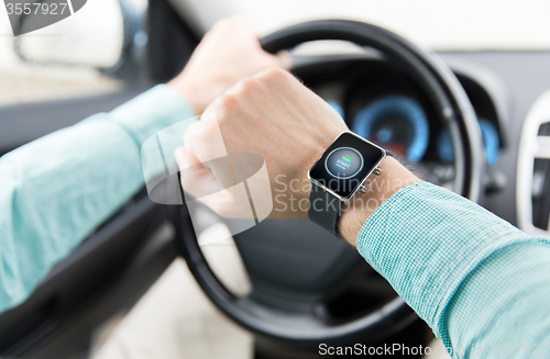 Image of hands with starter icon on smartwatch driving car