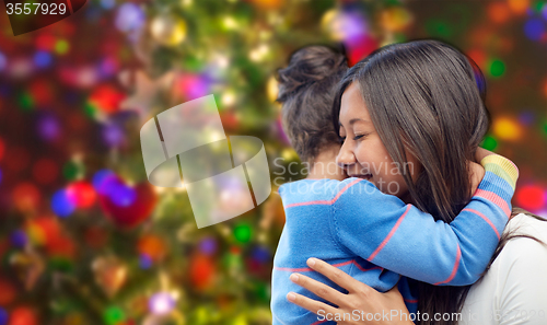 Image of happy mother and daughter hugging over lights