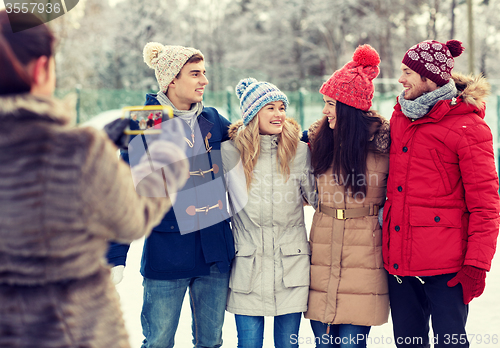 Image of happy friends taking picture with smartphone