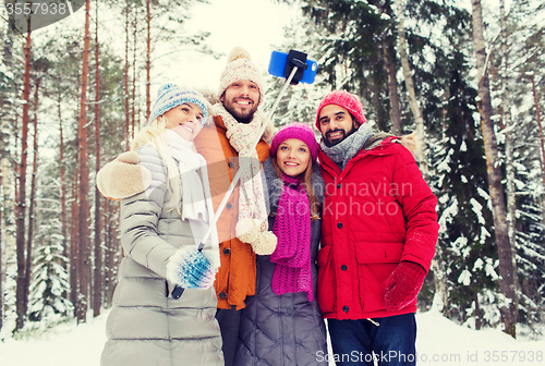 Image of smiling friends with smartphone in winter forest