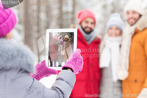 Image of happy friends with tablet pc in winter forest