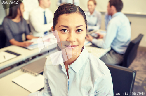 Image of group of smiling businesspeople meeting in office