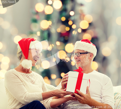 Image of happy senior couple with gift box at home