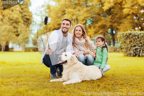 Image of happy family with dog taking selfie by smartphone