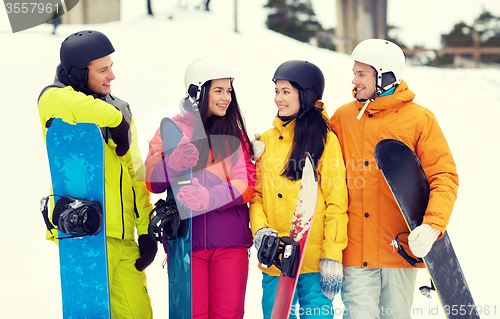 Image of happy friends in helmets with snowboards talking