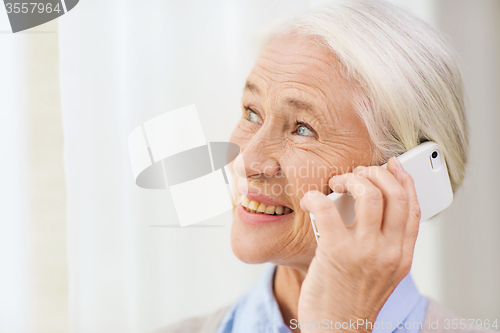 Image of senior woman with smartphone calling at home