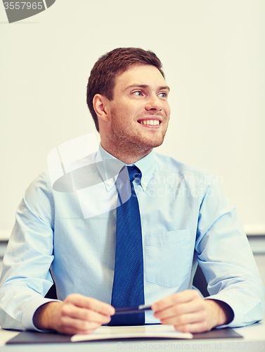 Image of smiling businessman sitting in office