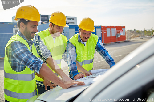 Image of close up of builders with blueprint on car hood