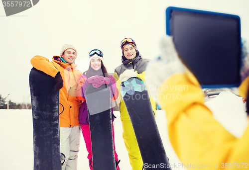 Image of happy friends with snowboards and tablet pc