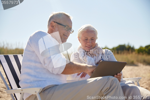 Image of happy senior couple with tablet pc on summer beach