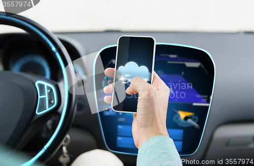 Image of close up of male hand with smartphone driving car