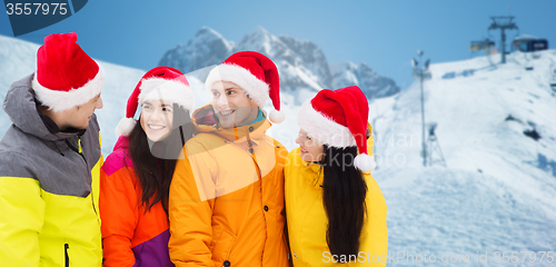 Image of happy friends in santa hats and ski suits outdoors