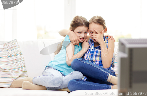 Image of scared little girls watching horror on tv at home