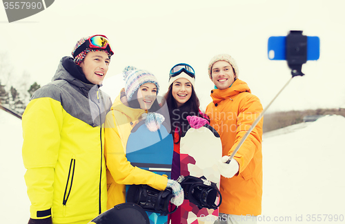 Image of happy friends with snowboards and smartphone