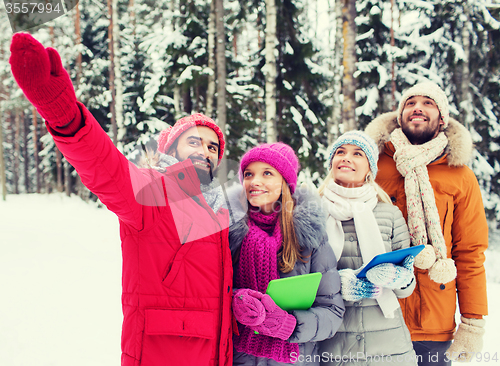 Image of smiling friends with tablet pc in winter forest