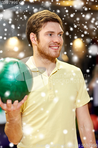 Image of happy young man holding ball in bowling club