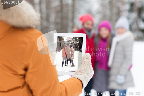 Image of happy friends with tablet pc in winter forest