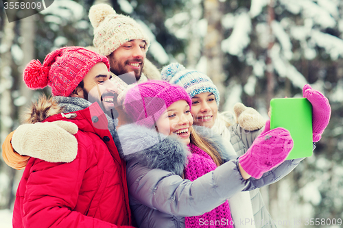 Image of smiling friends with tablet pc in winter forest
