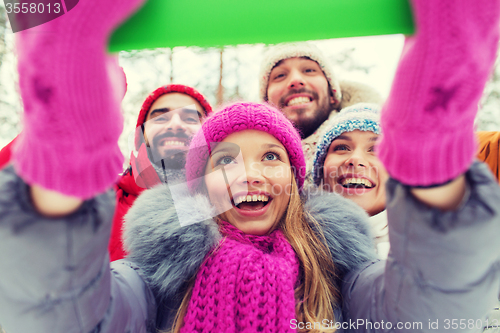 Image of smiling friends with tablet pc in winter forest