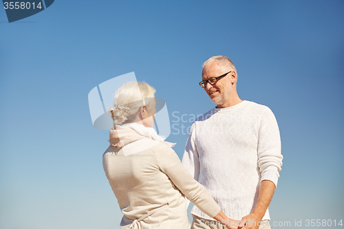 Image of happy senior couple holding hands outdoors