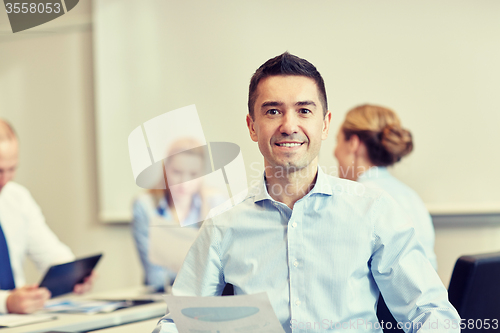 Image of smiling group of businesspeople meeting in office