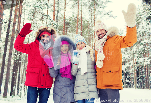 Image of group of friends waving hands in winter forest