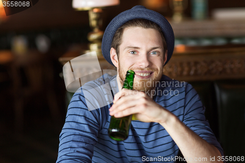 Image of happy young man drinking beer at bar or pub