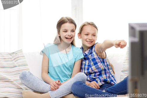 Image of two happy little girls watching tv at home