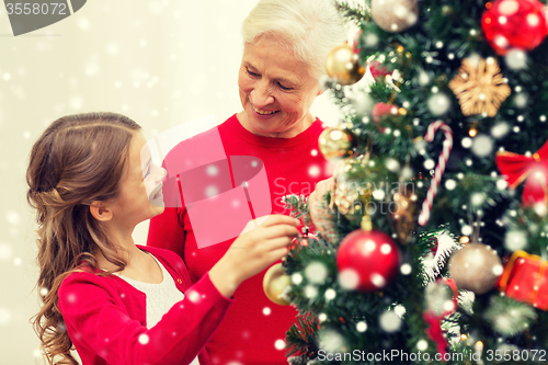 Image of smiling family decorating christmas tree at home