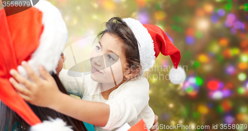 Image of happy mother and little girl in santa hats