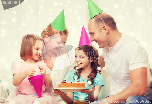 Image of happy family with two kids in party hats at home