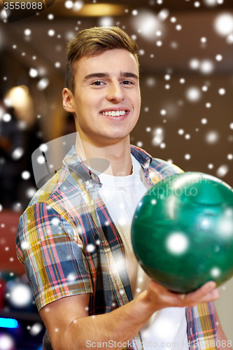 Image of happy young man holding ball in bowling club