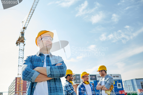 Image of group of smiling builders in hardhats outdoors