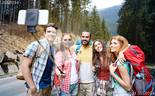 Image of friends with backpack taking selfie by smartphone