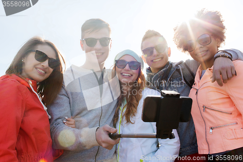 Image of friends taking selfie with smartphone on stick