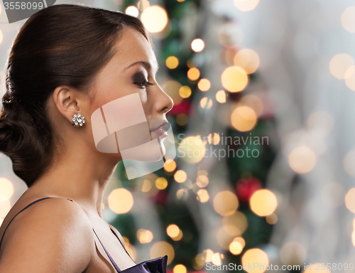 Image of woman with diamond earring over christmas lights