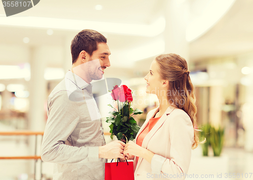 Image of happy young couple with flowers in mall