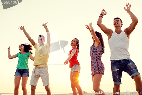 Image of smiling friends dancing on summer beach