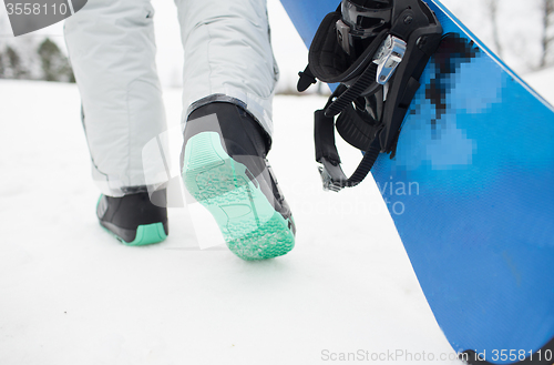 Image of close up of snowboarder walking with snowboard